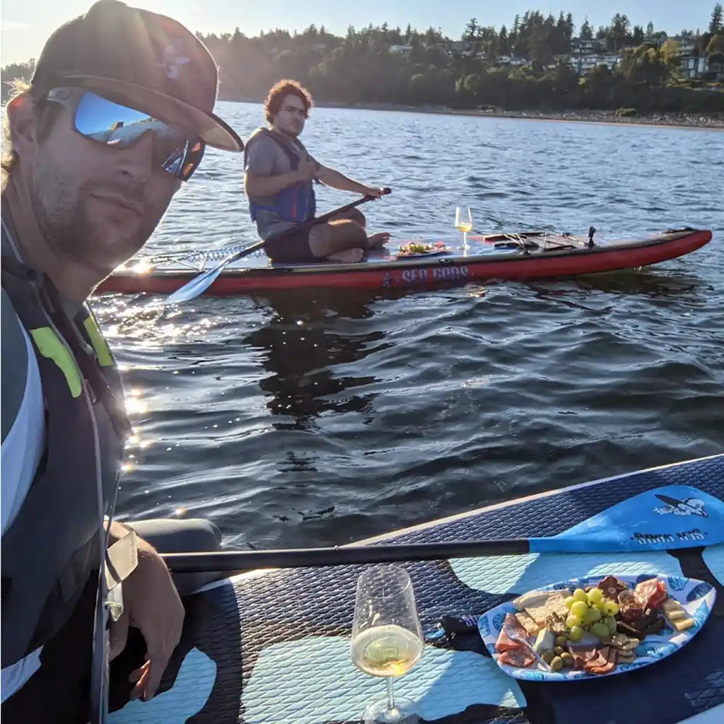 Group of men on sea gods stand up paddle boards enjoying comradery and charcuterie