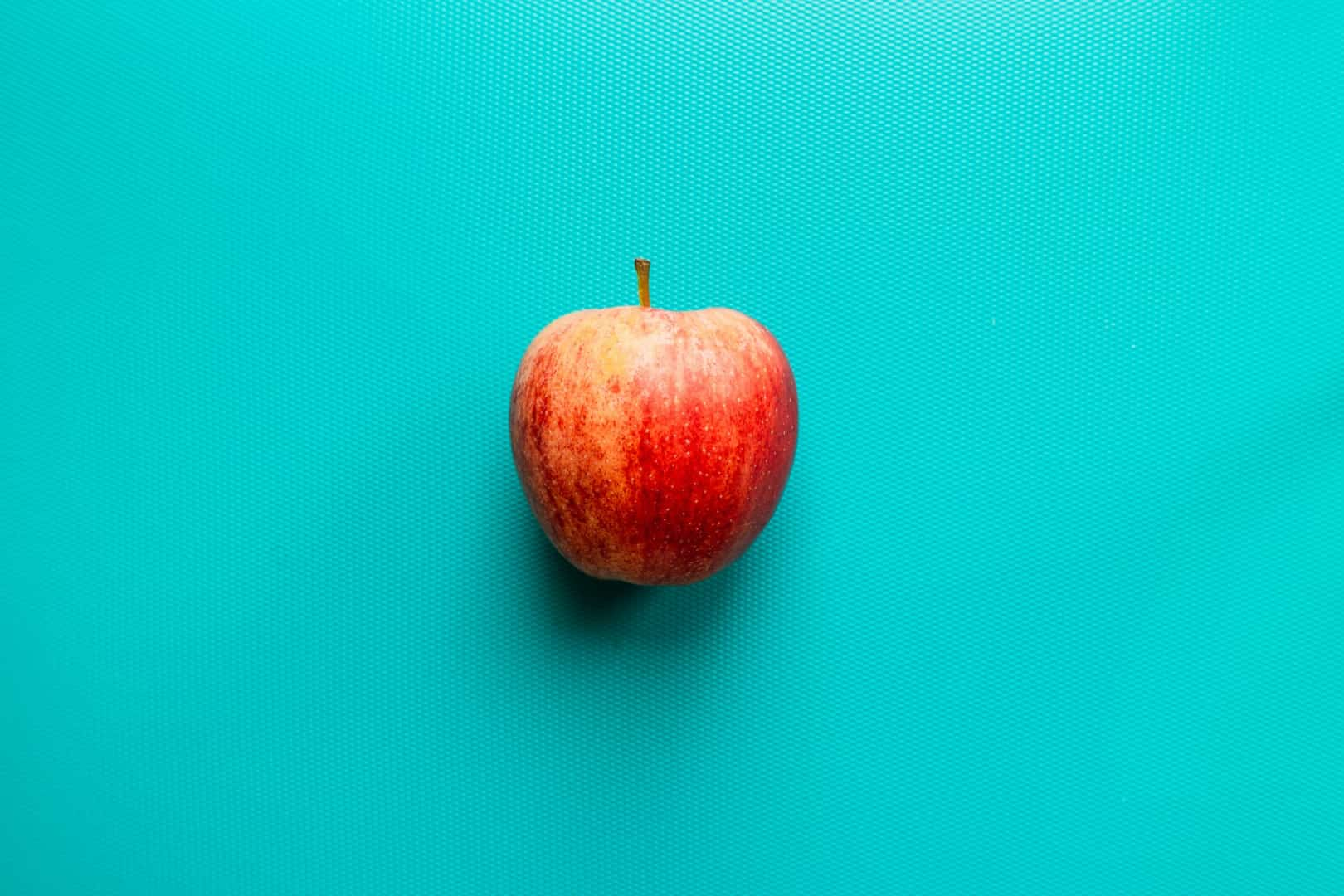 A red apple against a blue-green background