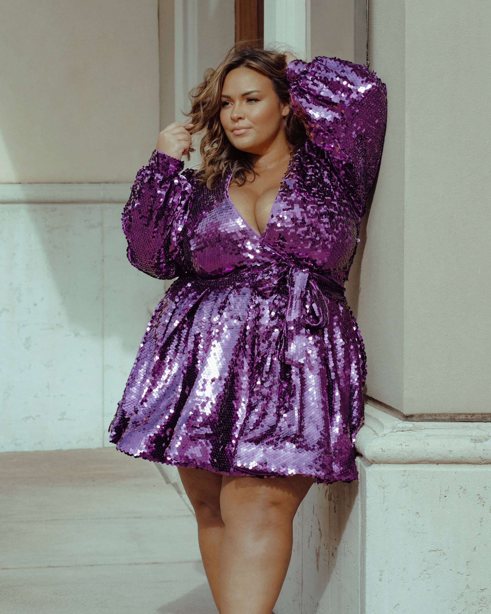 A woman wearing a purple glitter wrap dress