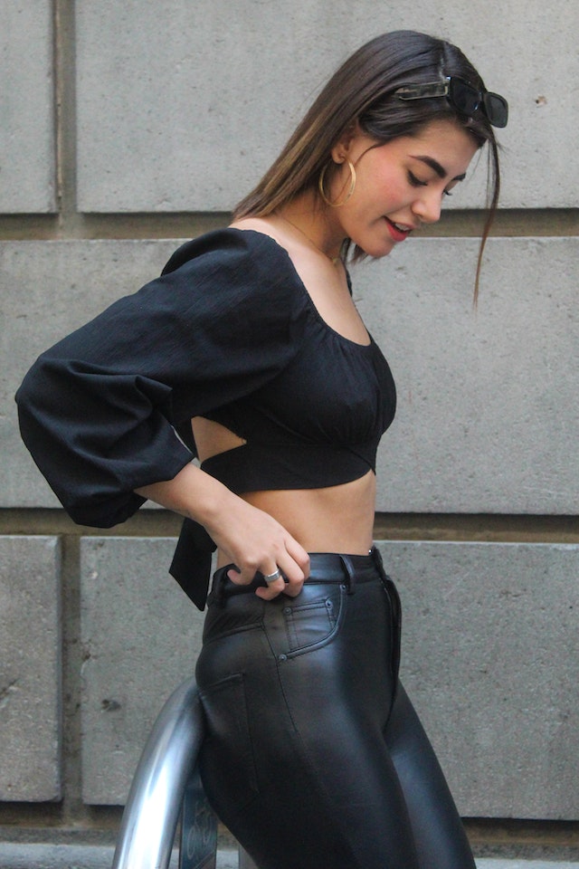 A young woman wearing a crop top with leather pants