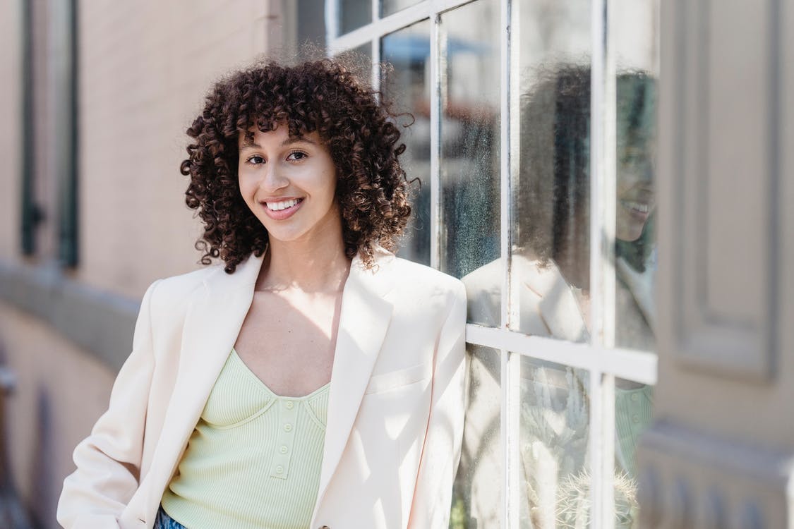 A young woman with curly brown hair smiling