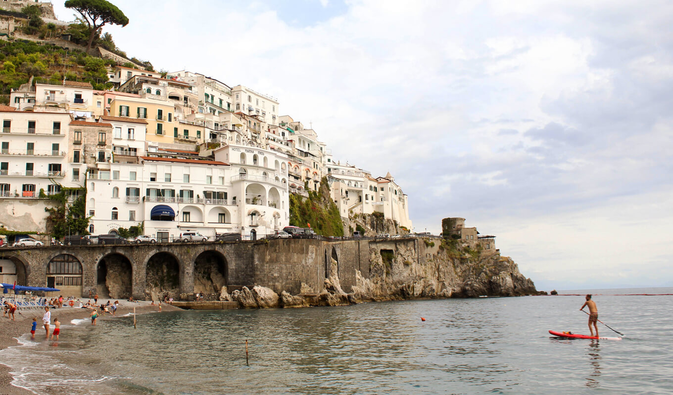 Man on a paddle board near concrete buildings