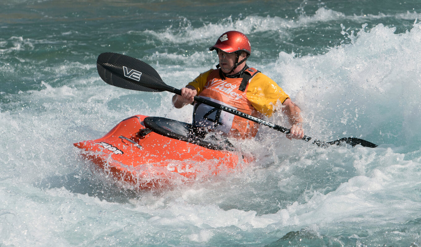 Man whitewater kayaking using an orange kayak