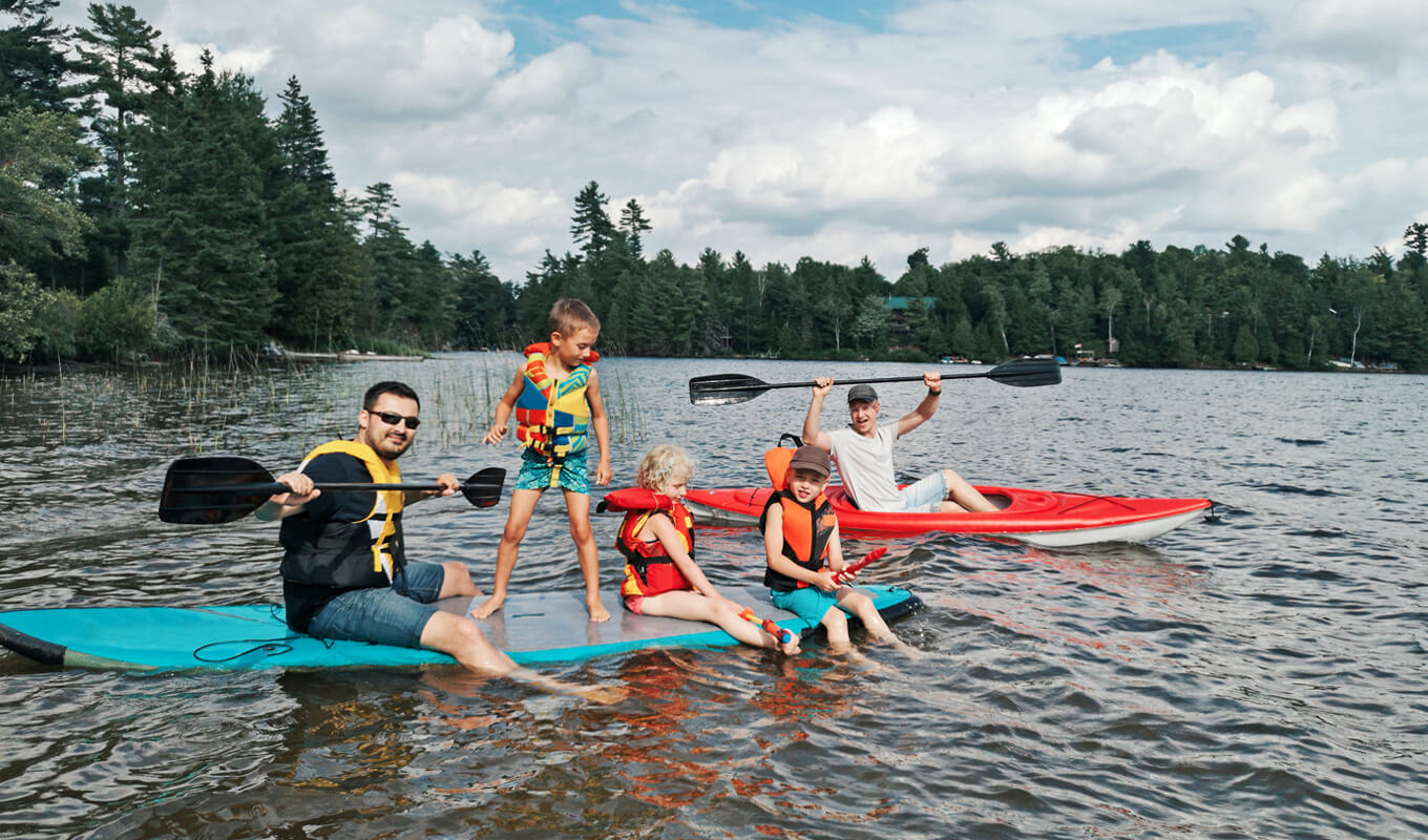 Father with kids swimming on a paddle board on lake river