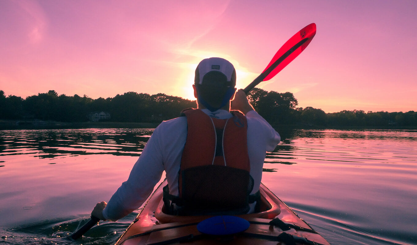 Man kayaking on a red life jacket