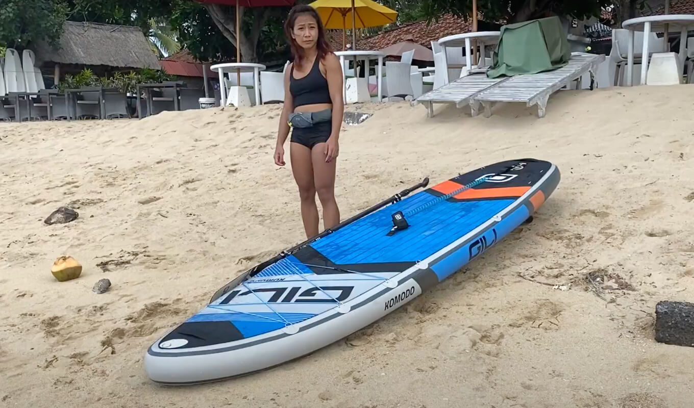 Woman wearing an onyx inflatable belt pfd standing near a komodo inflatable paddle board