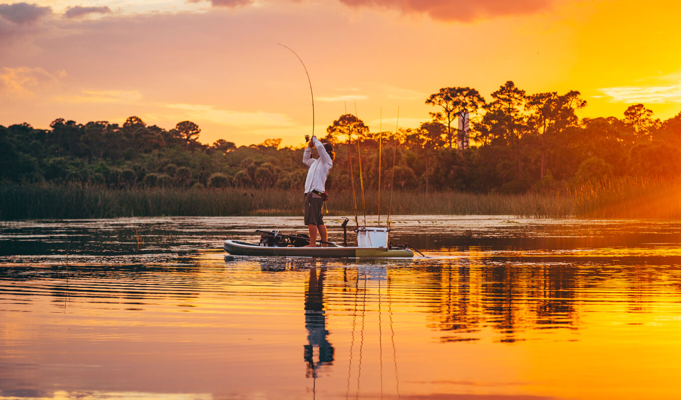 Mann fischt auf einem See mit SUP-Board