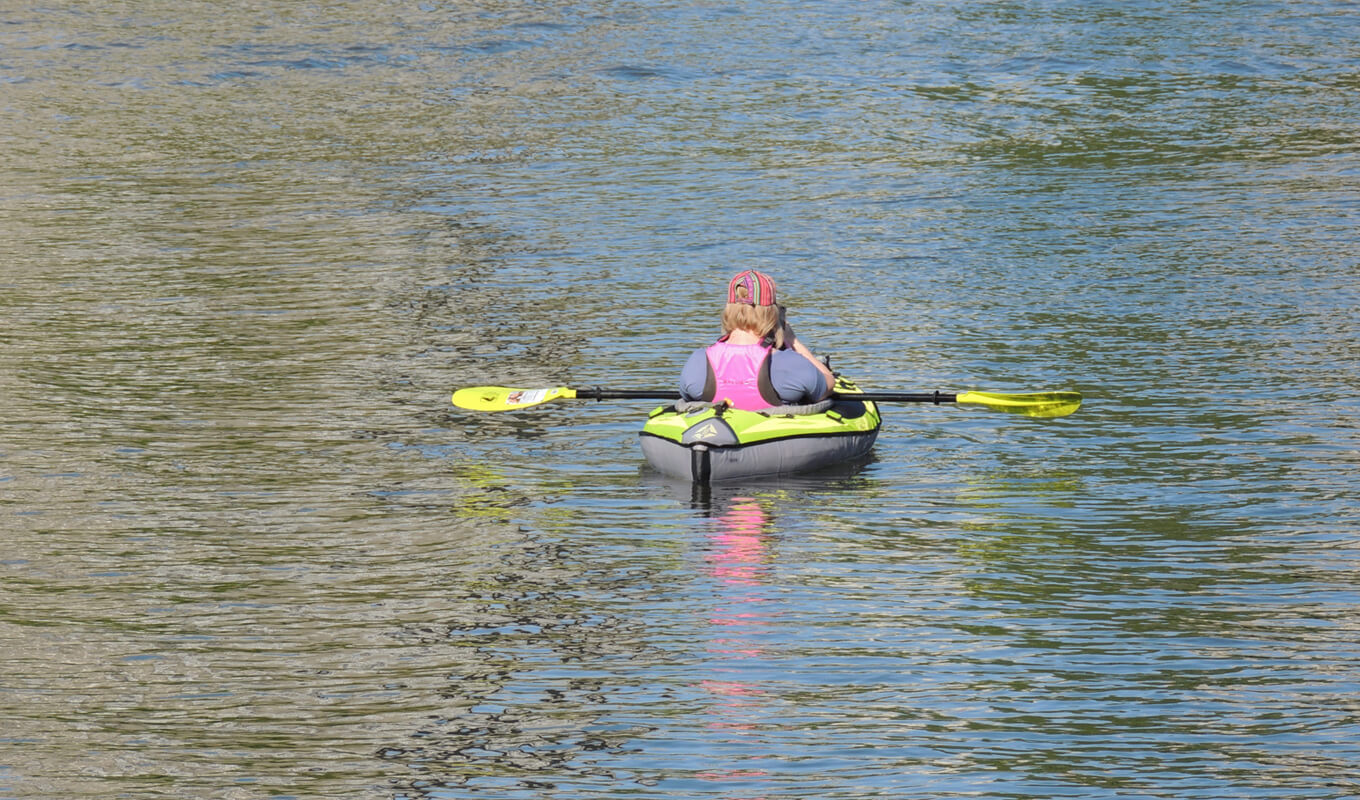 Women  wearing a life jacket on a green inflatable kayak