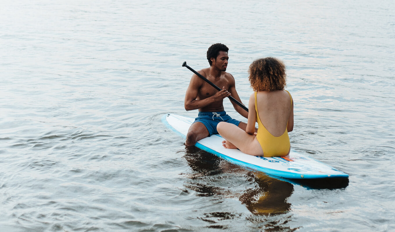 Man and a woman paddle boarding on a soft top paddle board