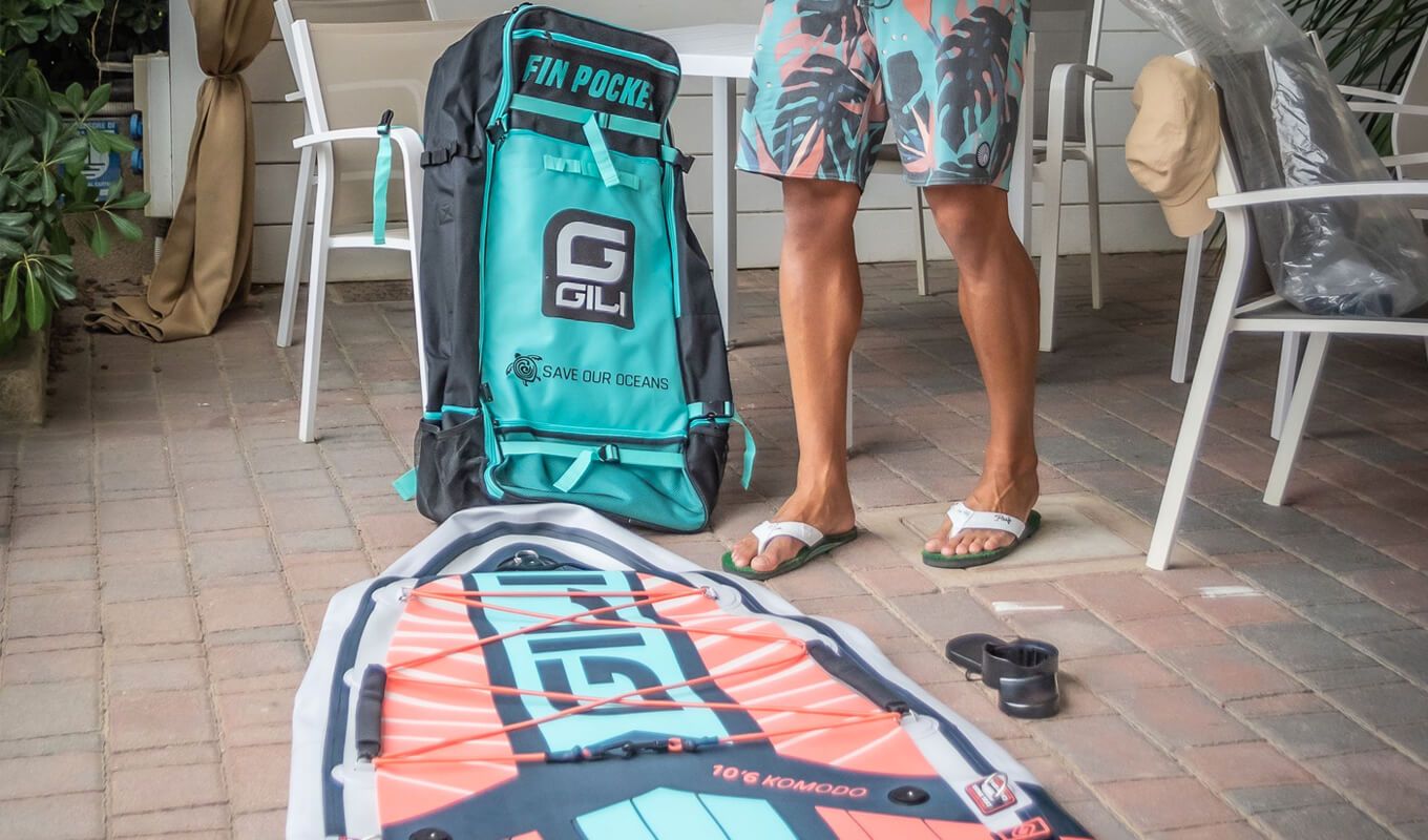 Man inflating a gili inflatable paddle board near SUP backpack