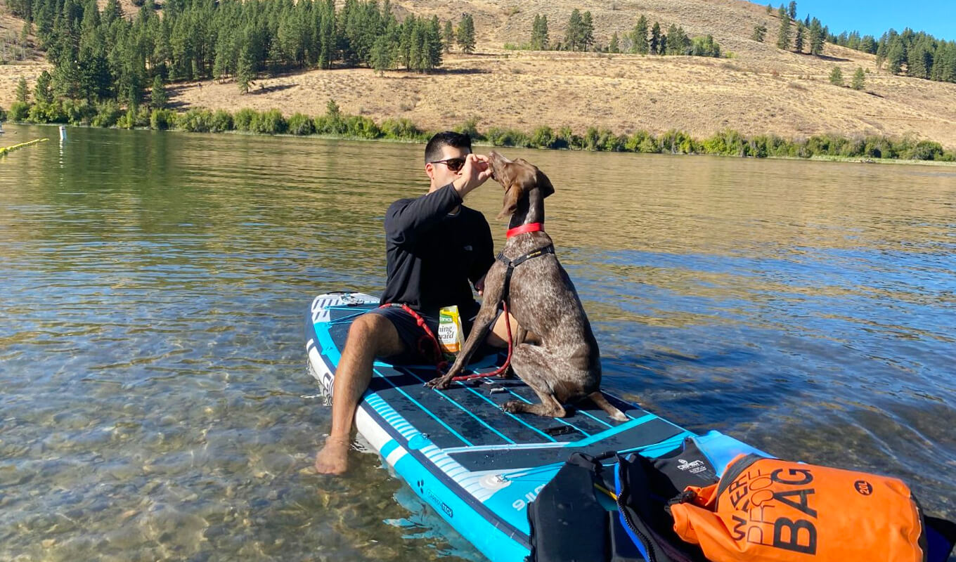 Mann paddelt mit seinem Hund auf einem GILI Meno