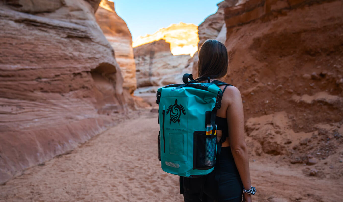 Woman walking between rocky mountains with GILI waterproof backpack