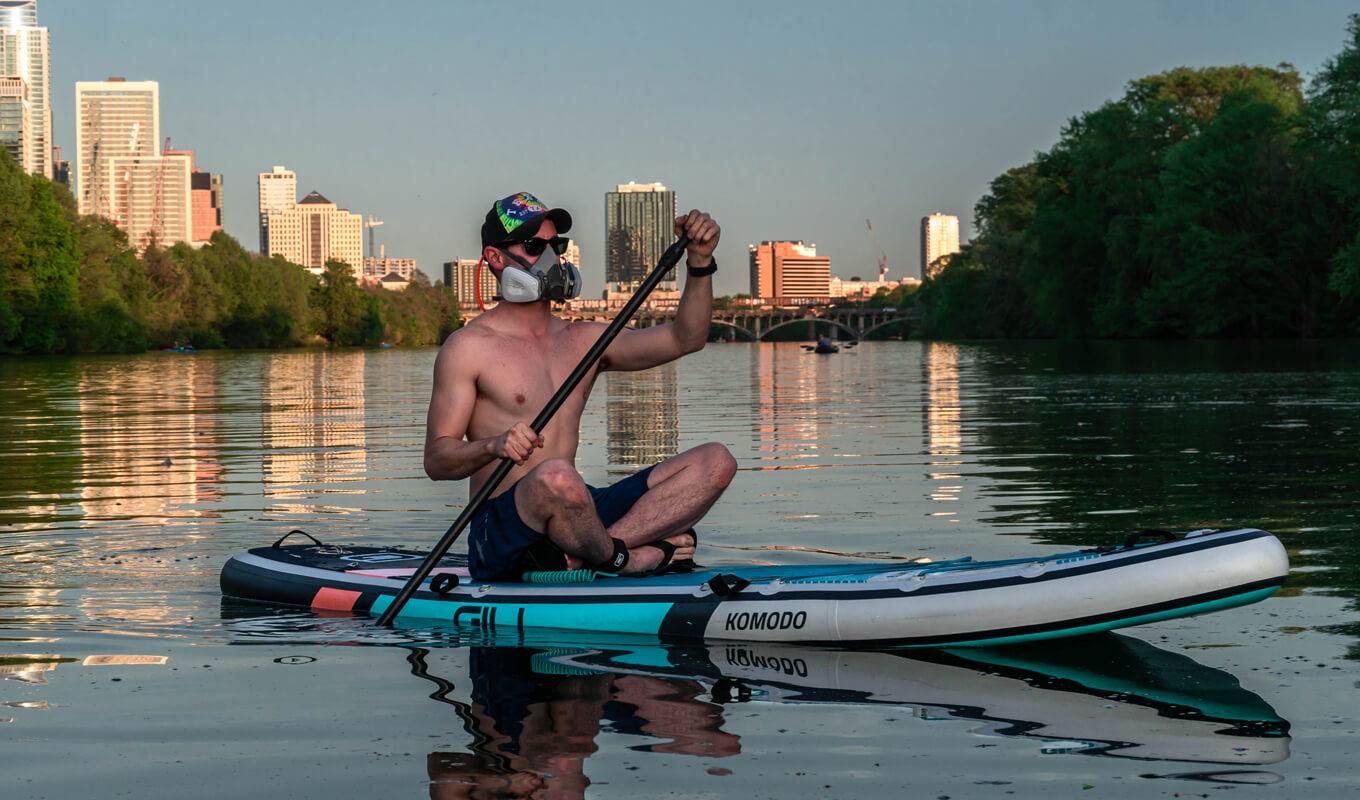 Man paddle boarding on lake wearing SUP ankle leash