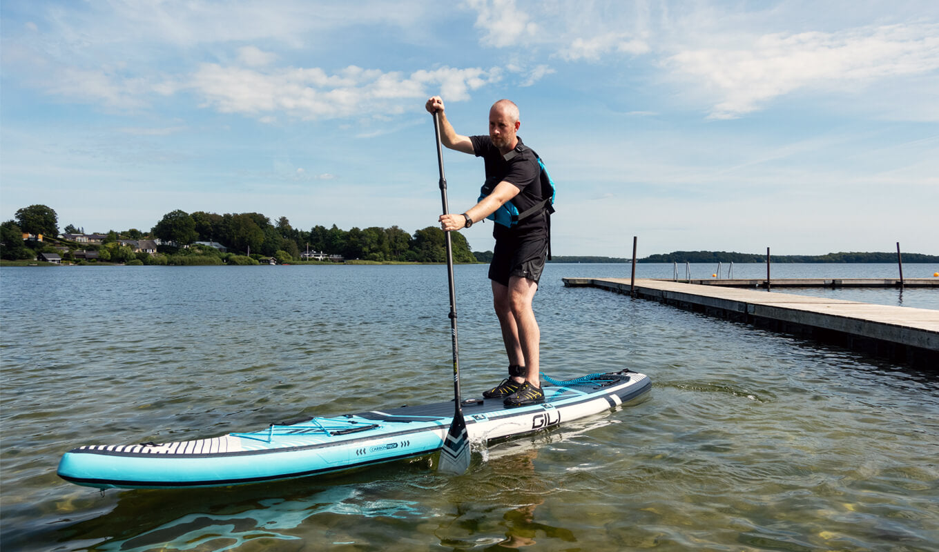 Mann mit schwarzem Hemd paddelt mit Meno Touring Inflatable SUP