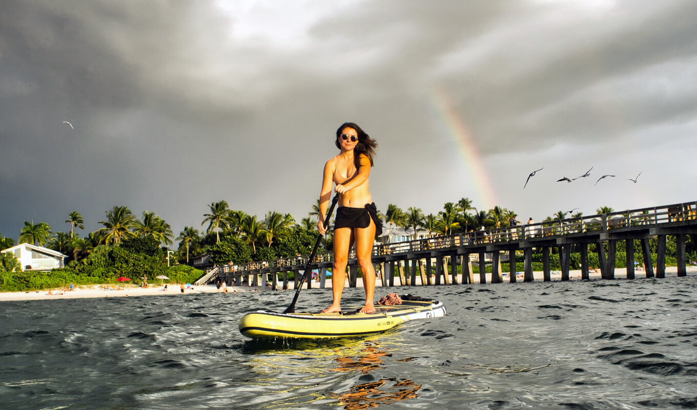 Woman paddle boarding on a body of water using GILI SUP