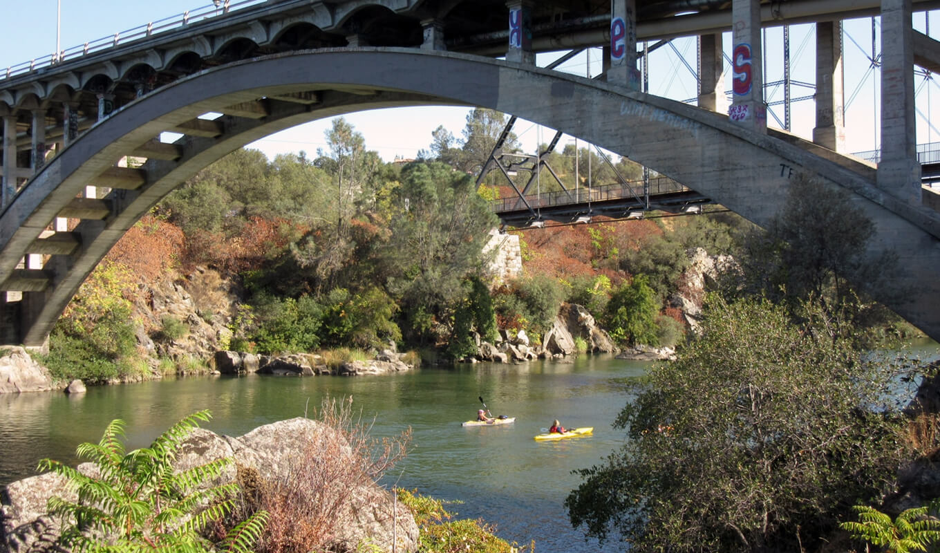 two man kayaking under the bridge