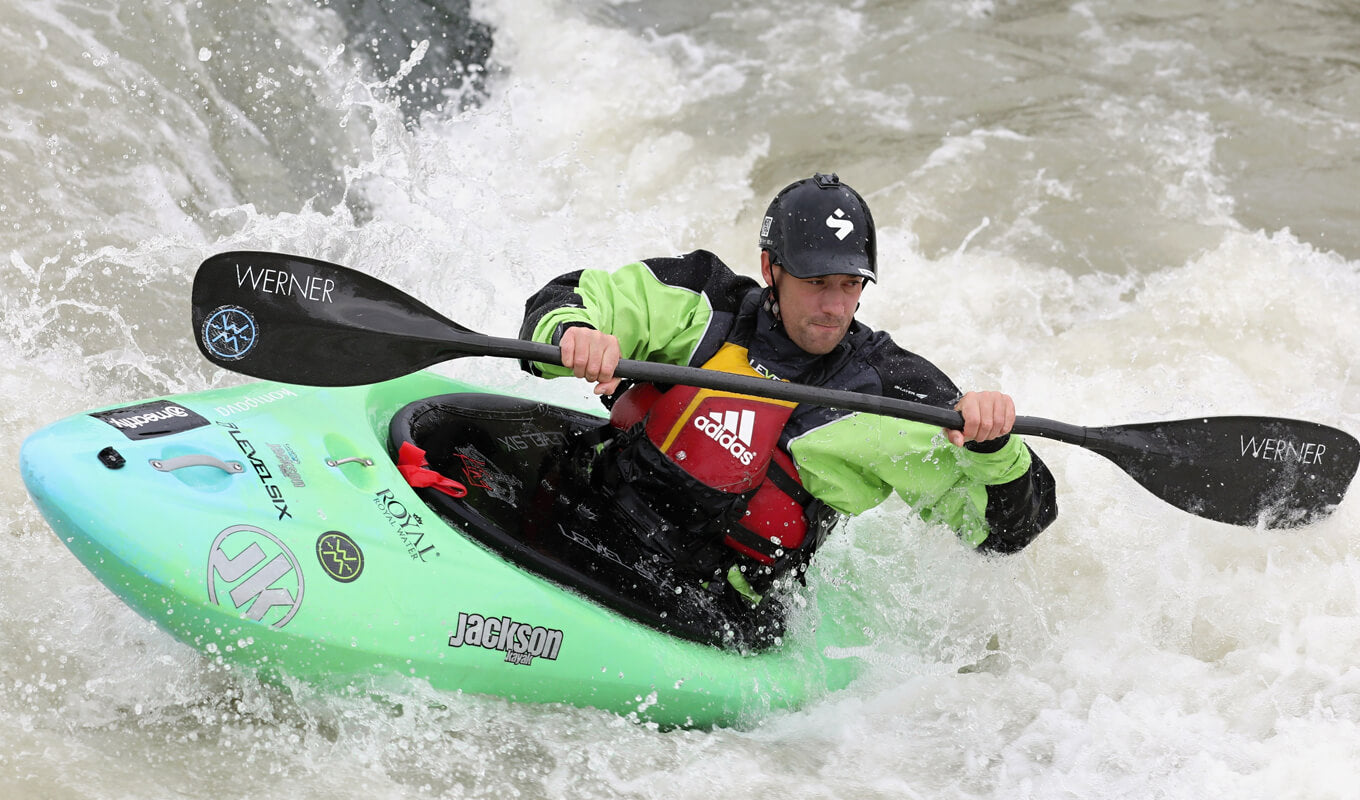 Man compete on a green whitewater kayak