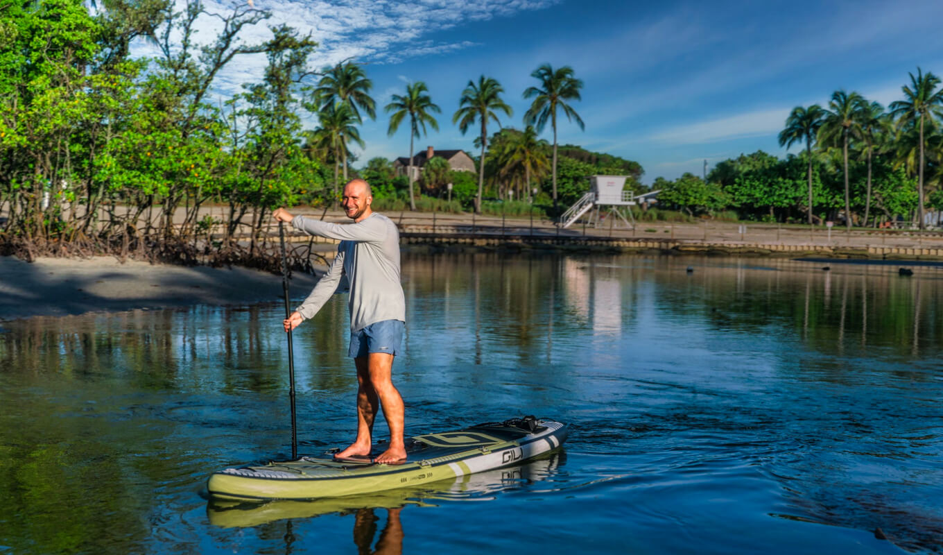 Man on a gray shirt paddle boarding on river