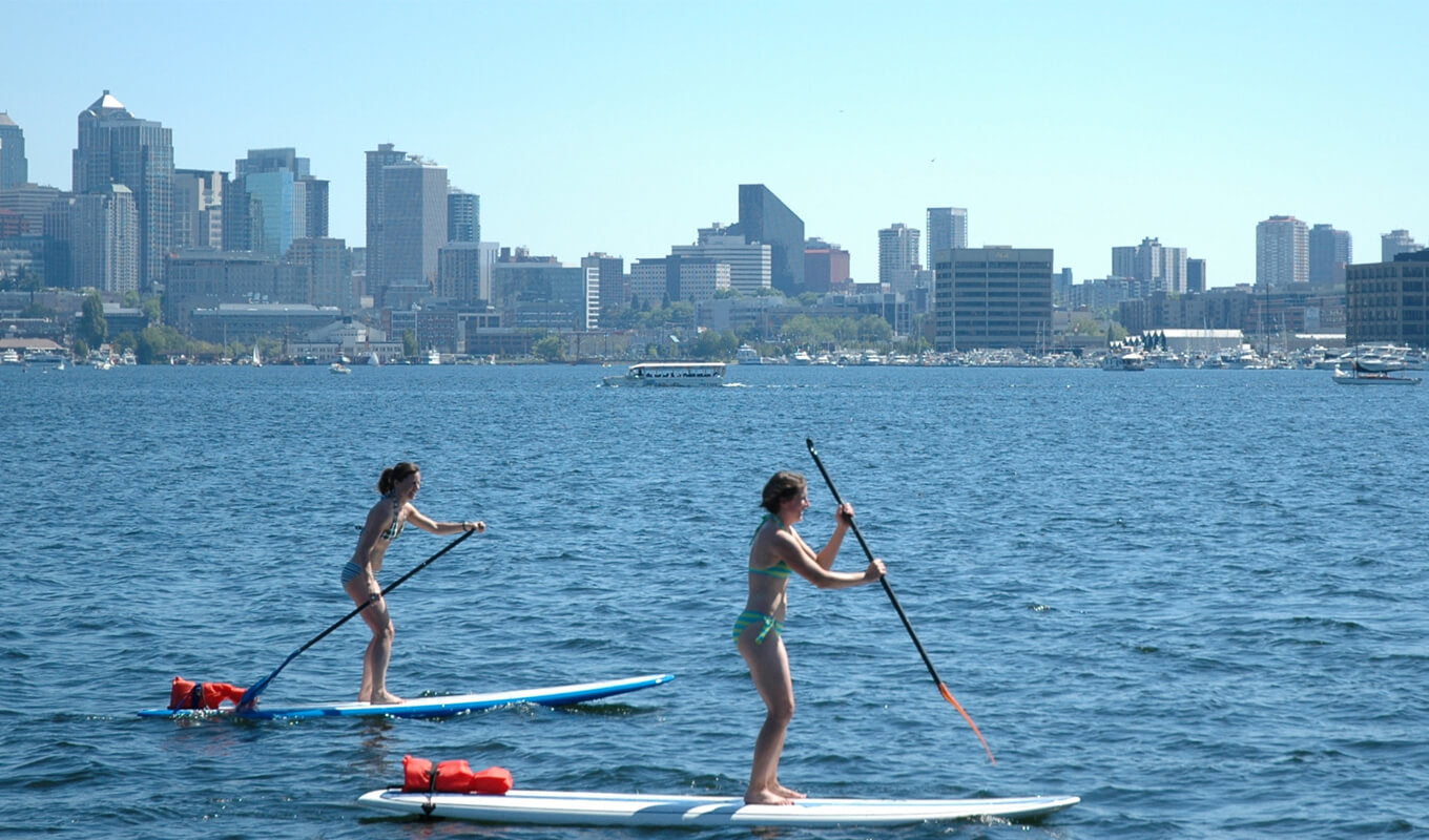 Two women paddle boarding in lake union