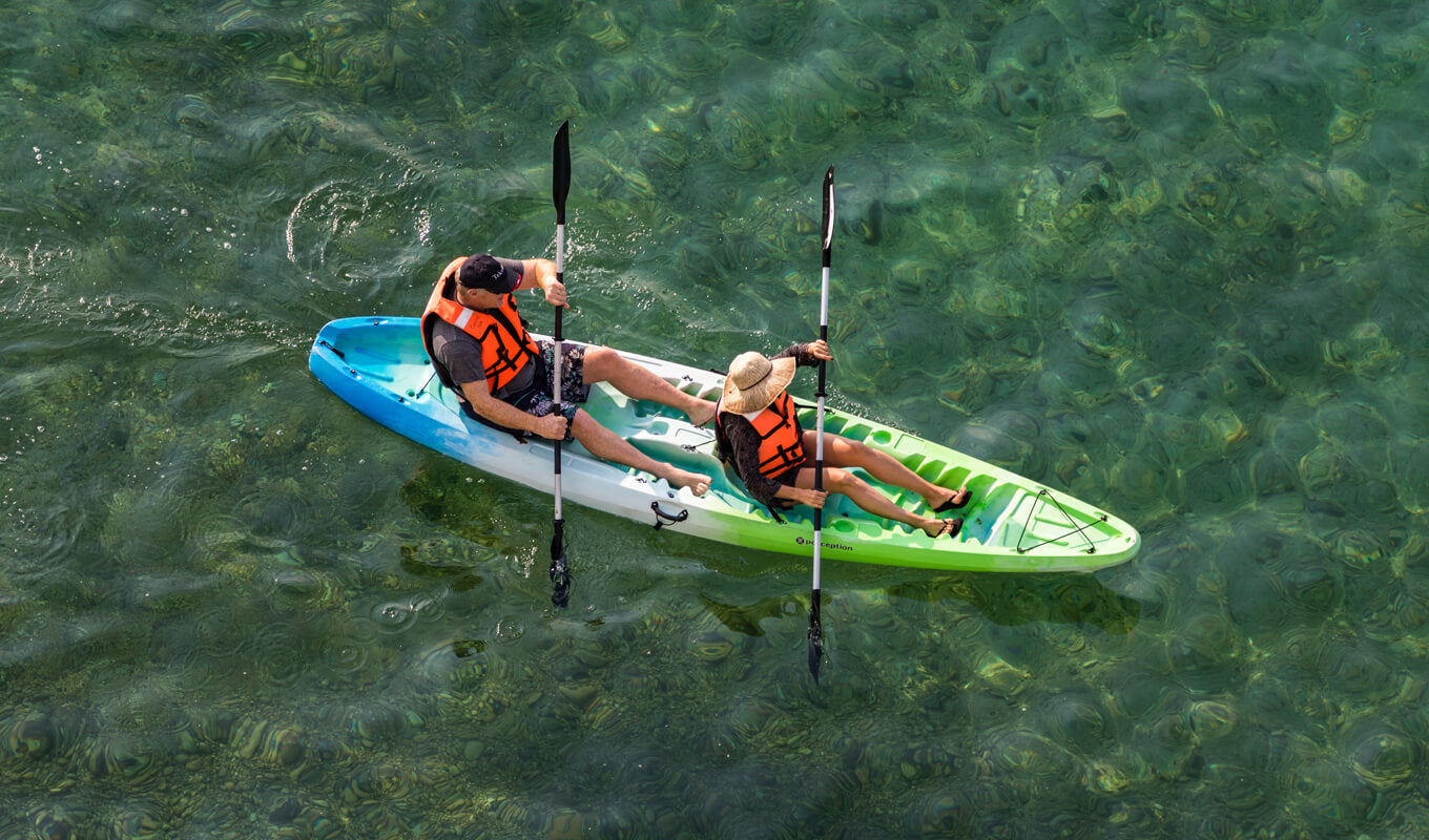 Man and a woman wearing an orange life jacket on a sit on top kayak