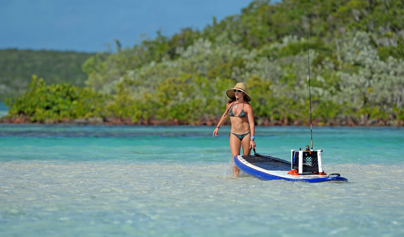 Woman fishing on a paddle board with tackle box