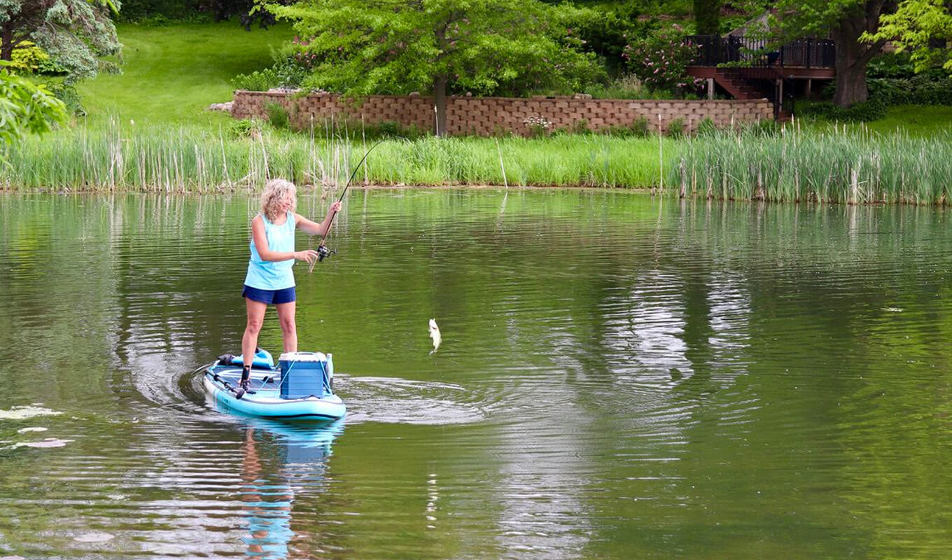 Frau fängt einen Fisch auf einem aufblasbaren SUP-Board von GILI