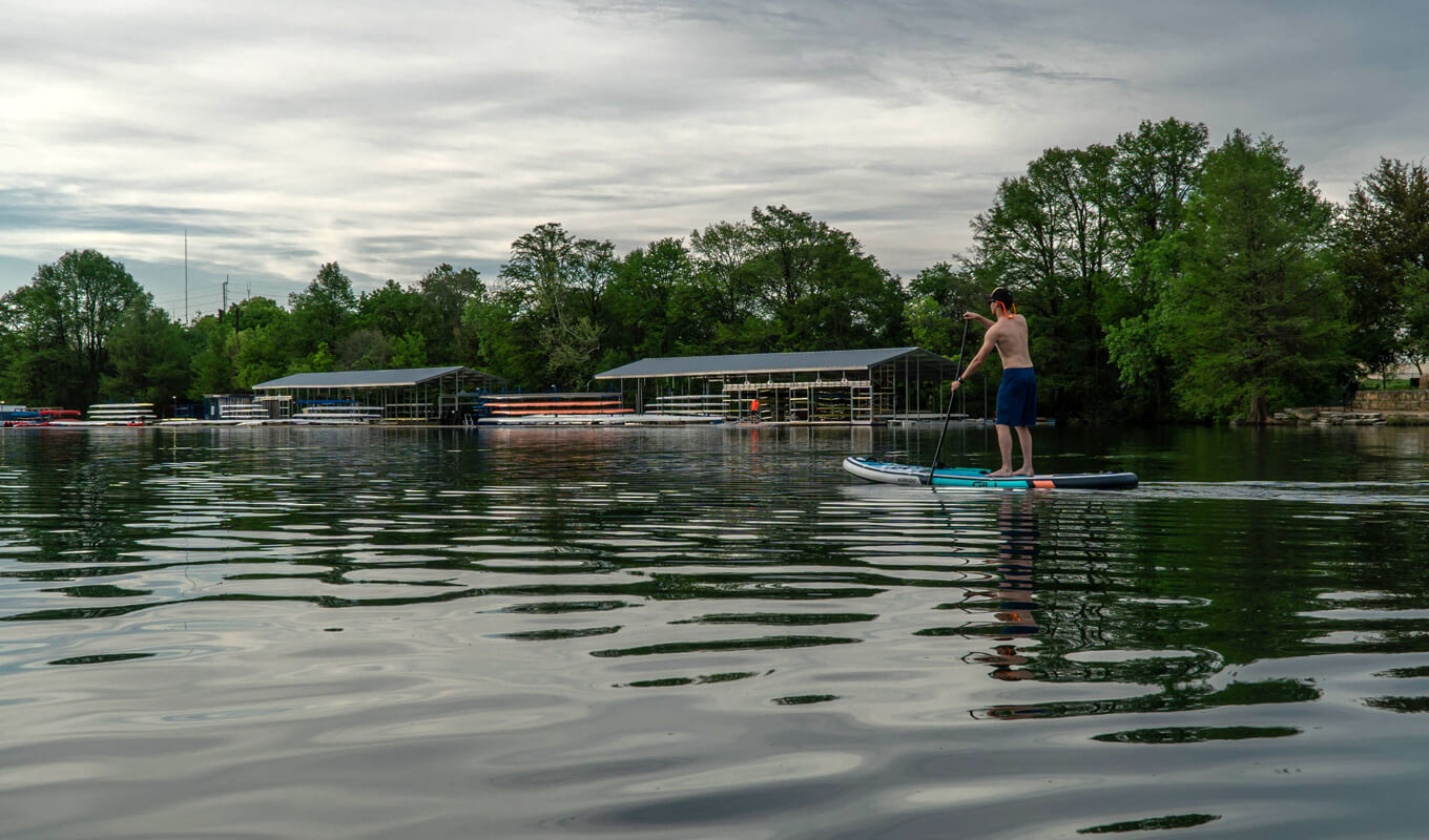 Man paddle boarding on a river using a GILI komodo inflatable paddle board