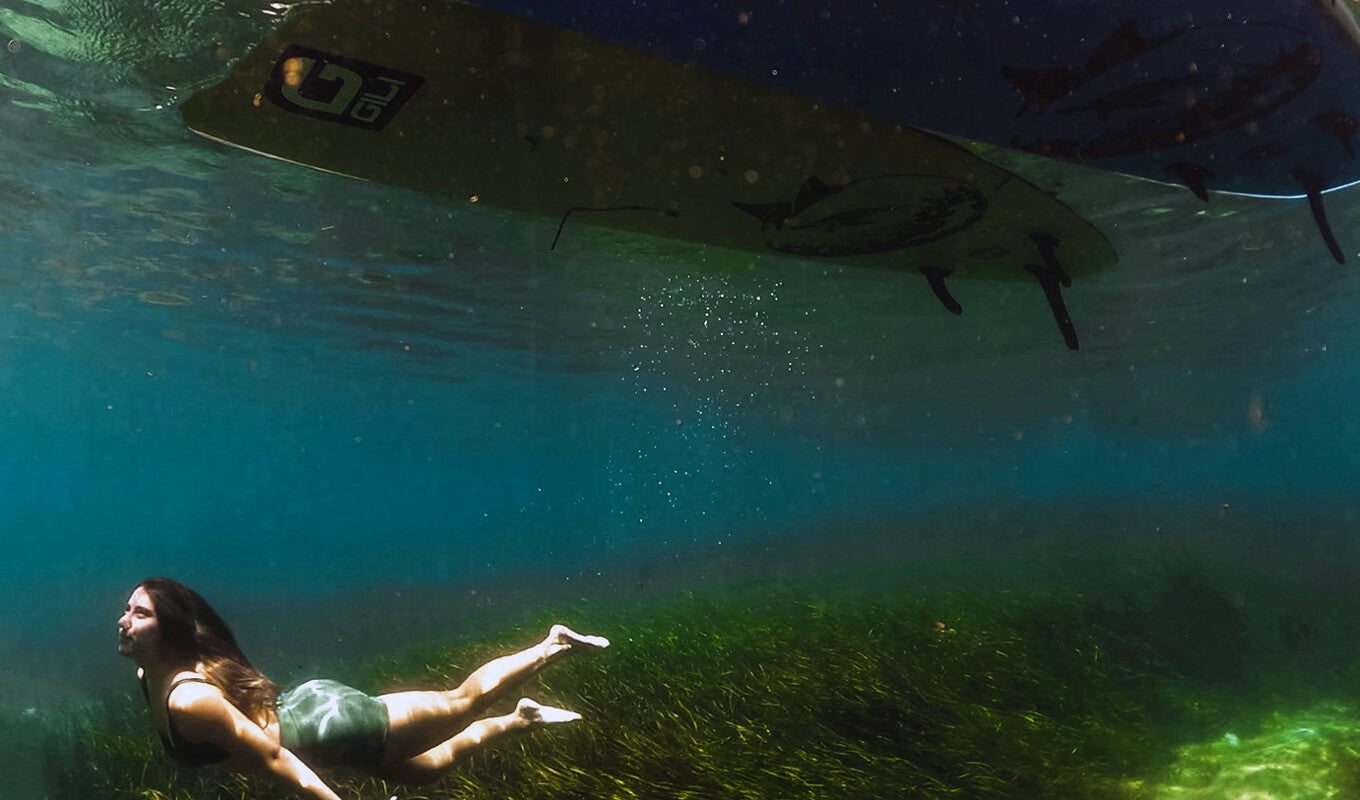 Women underwater above her two inflatable SUP