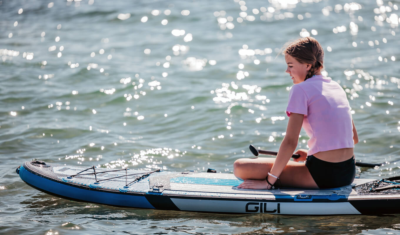 Young girl is sitting on her inflatable paddle board