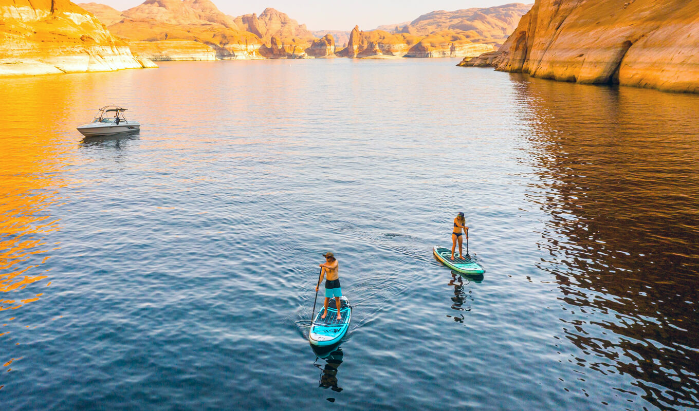 man and a woman paddle boarding near a boat