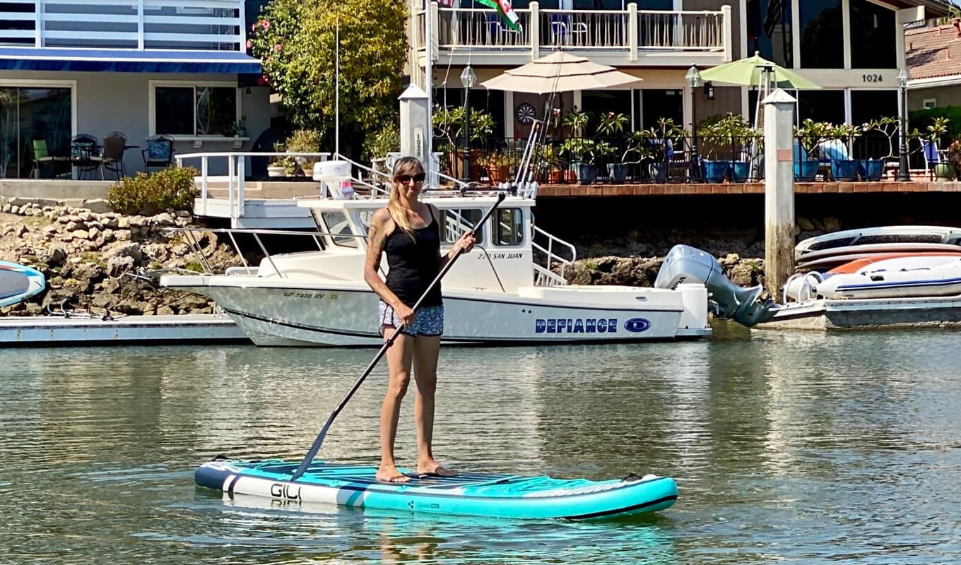 Woman paddle boarding in yacht dock