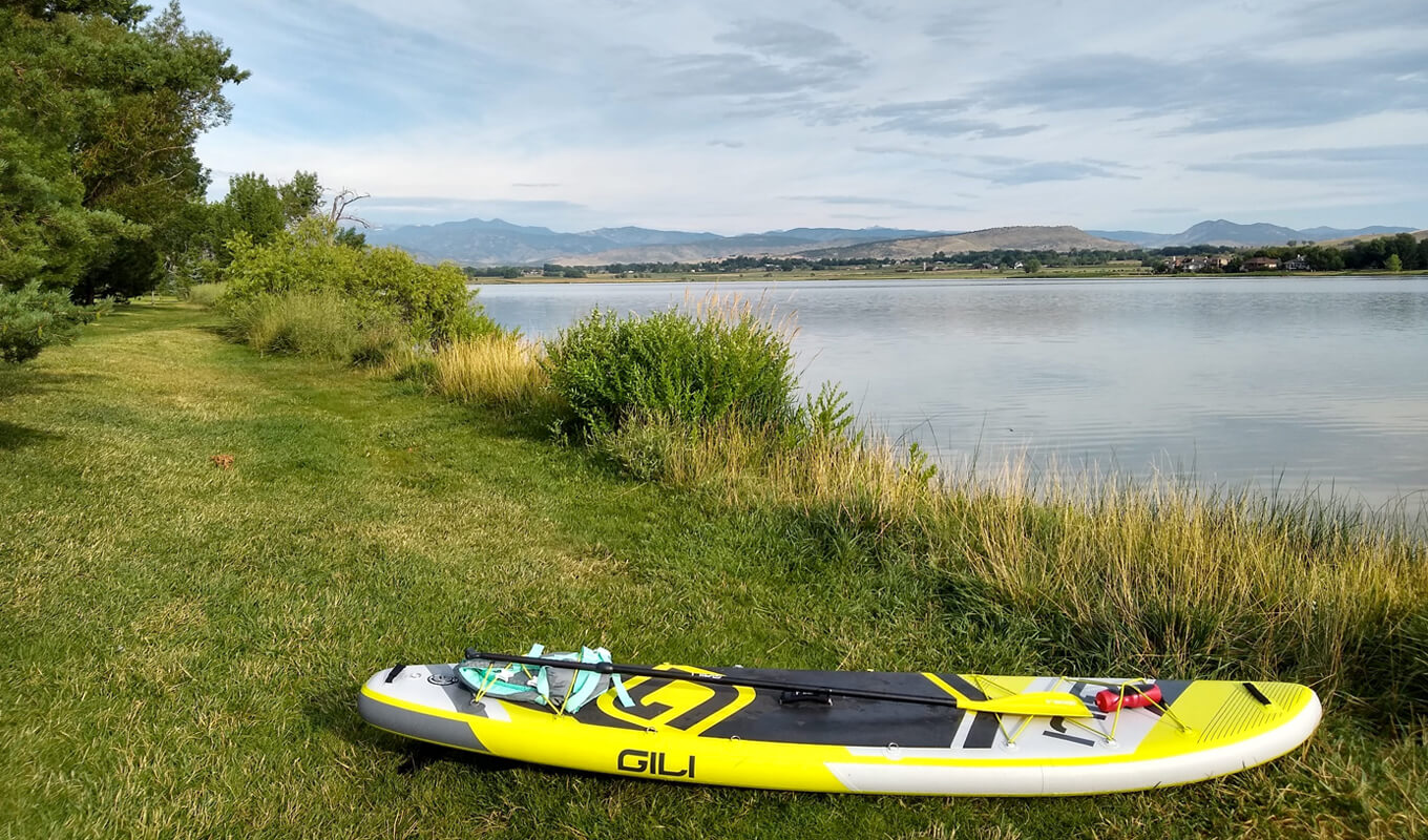 Yellow GILI Adventure inflatable paddle board beside lake