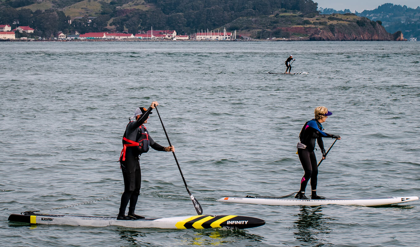 Two paddle boarders on a long inflatable paddle boards