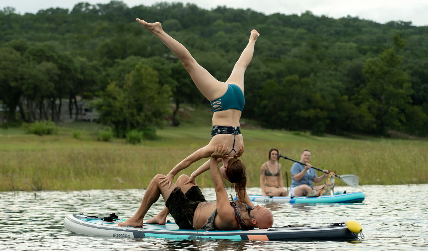 Man and a woman wearing a swimwear performing an advance yoga position