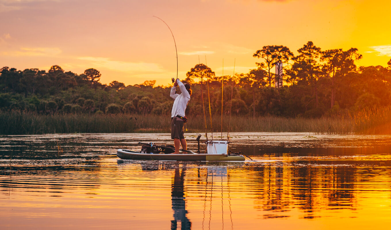 Mann fischt auf einem See mit SUP mit kompletter Einrichtung