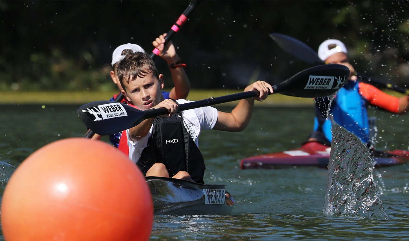 kids holding a black kayak paddle