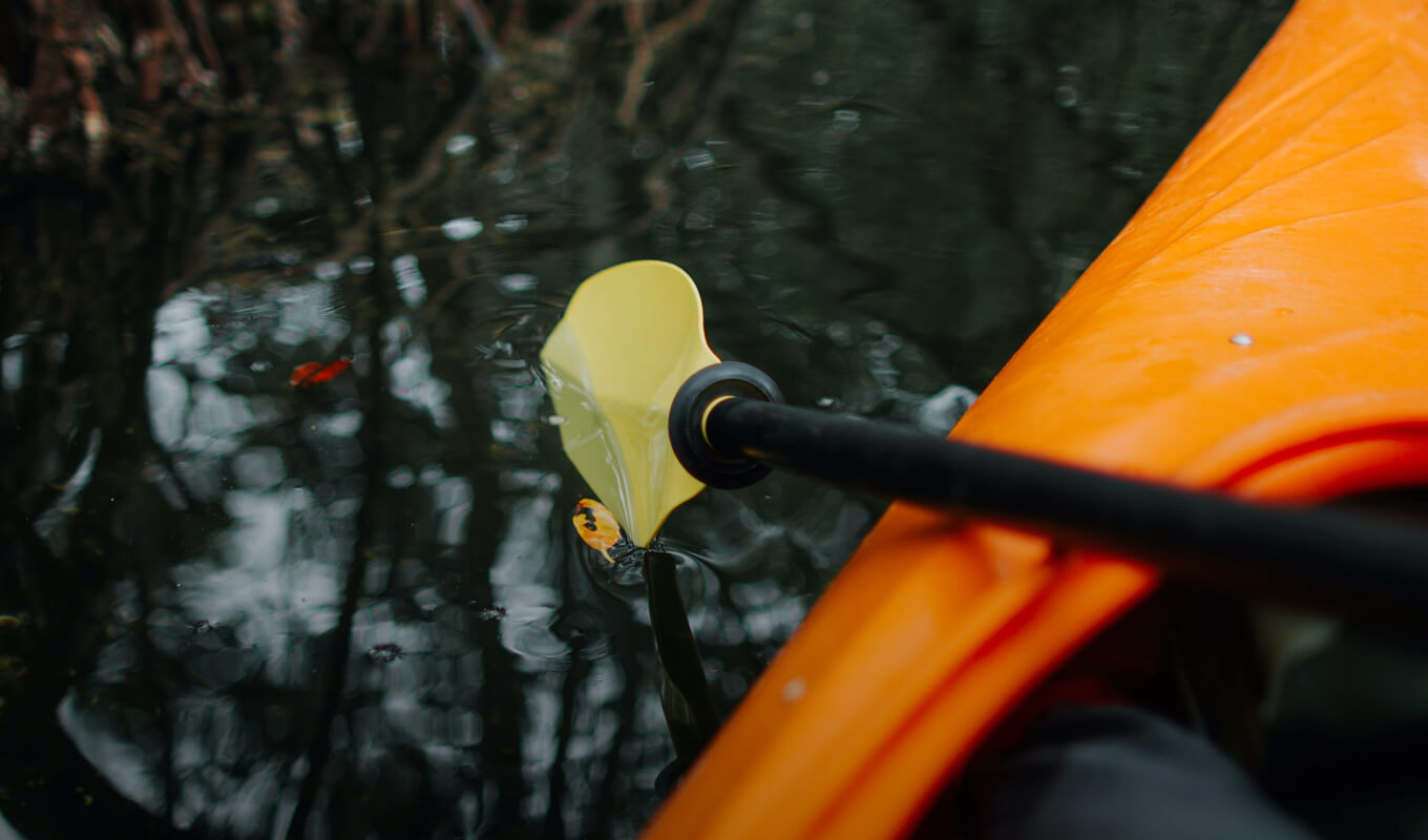 Orange kayak and yellow blade kayak paddle