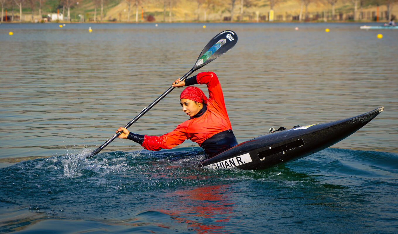 Woman on a red shirt on a kayak performing a draw stroke