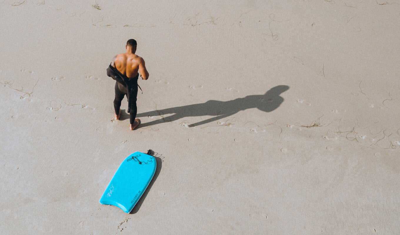 Man on a black wetsuit with a blue boogie board