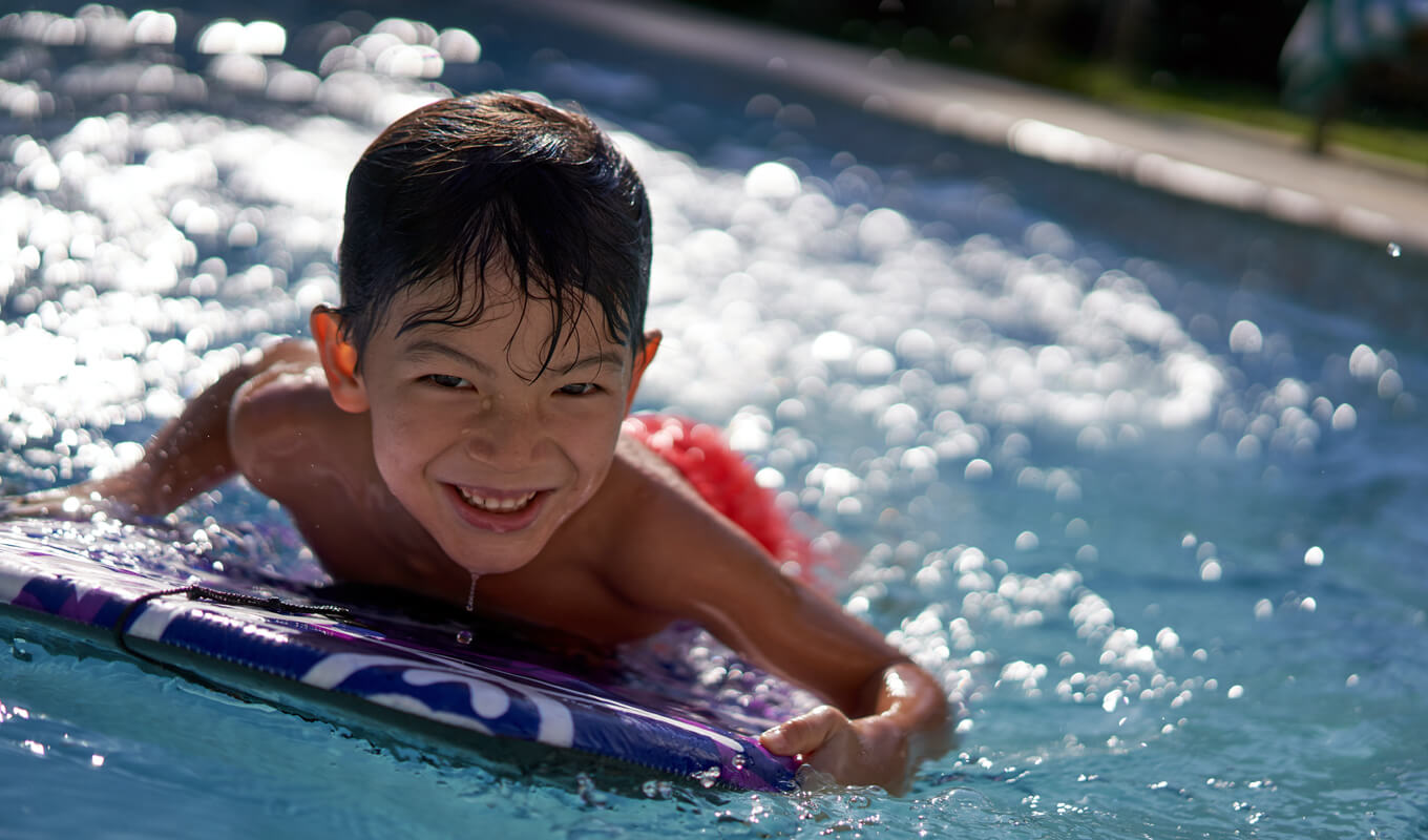 Kid with a boogie board swimming on a pool