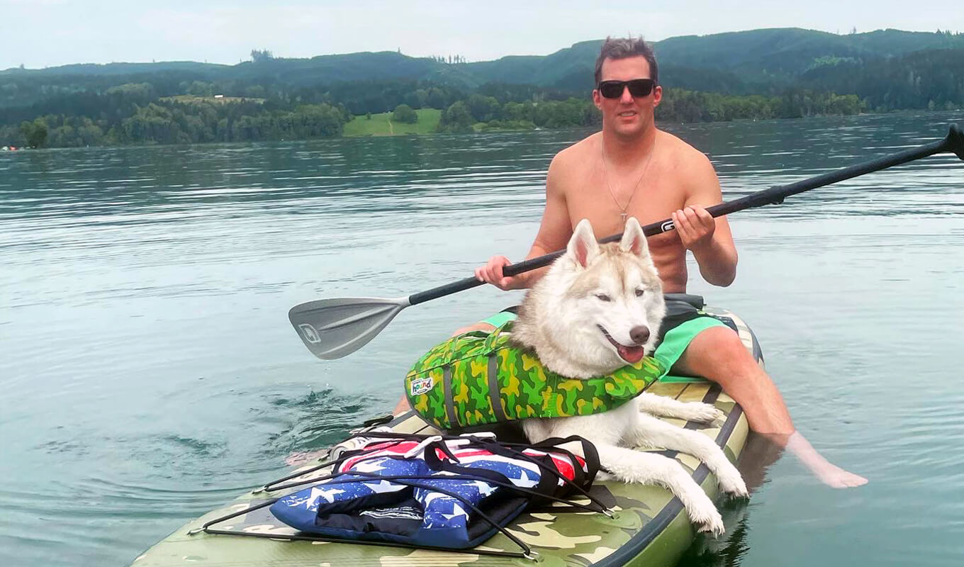 Man paddle boarding with his dog on a lake