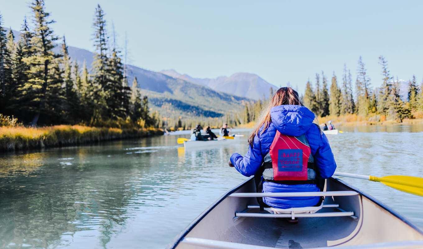 Woman canoeing behind kayakers on a lake