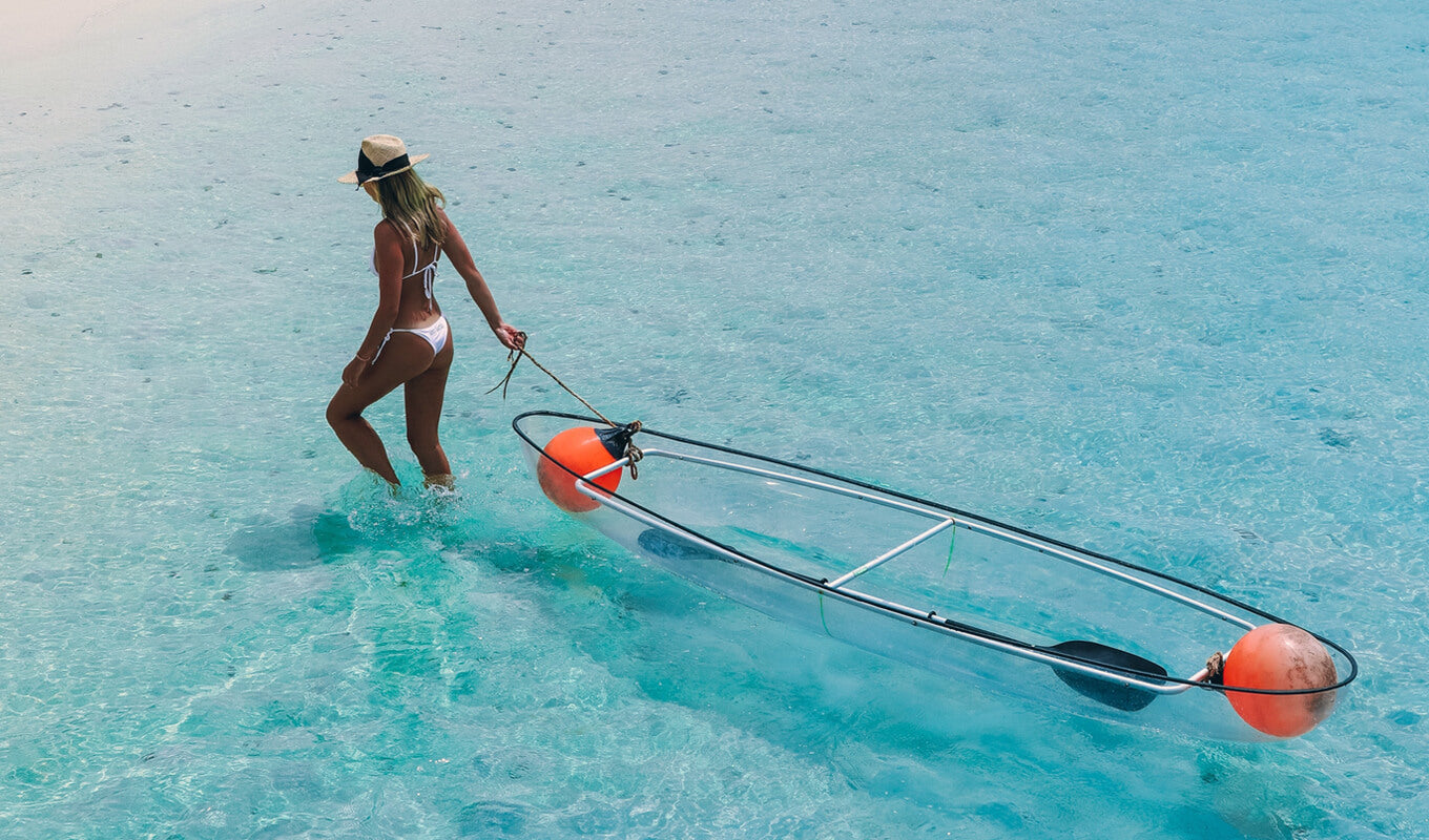 Woman dragging her clear bottom kayak on the shore