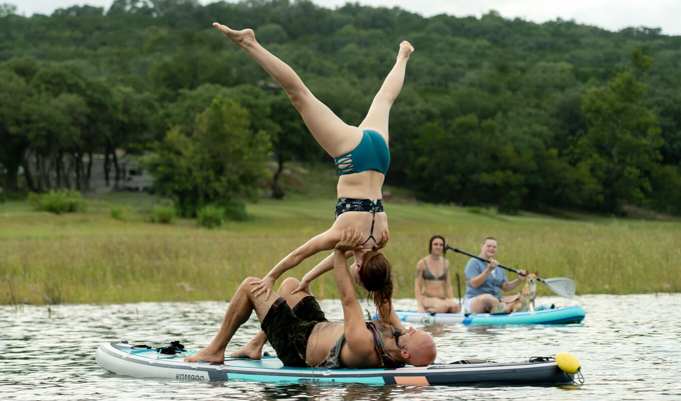 Mann und Frau, die eine fortgeschrittene Yoga-Pose auf aufblasbaren GILI-Komodo-Paddelbrettern ausführen
