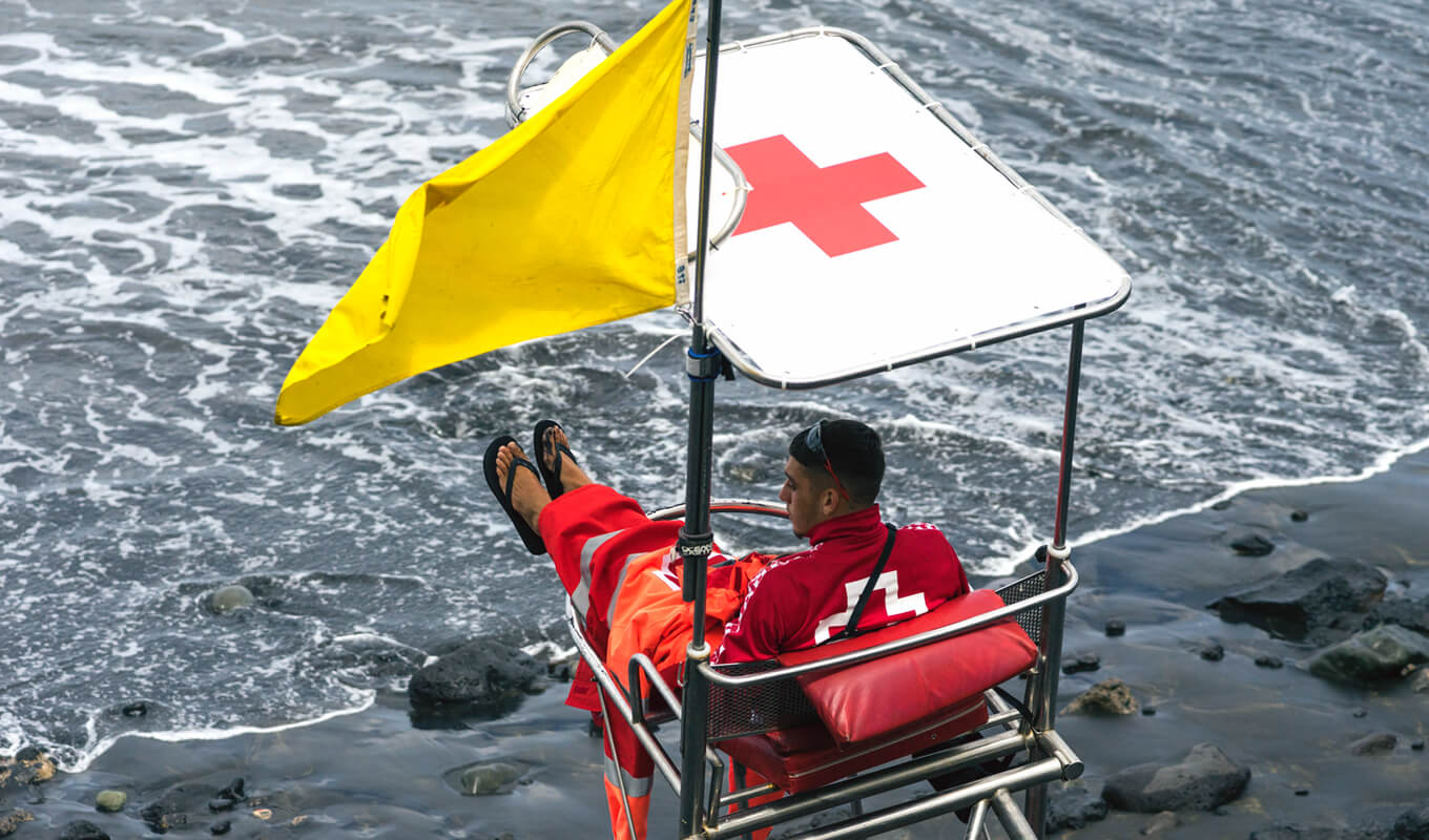 Mann sitzt auf Strandwachposten