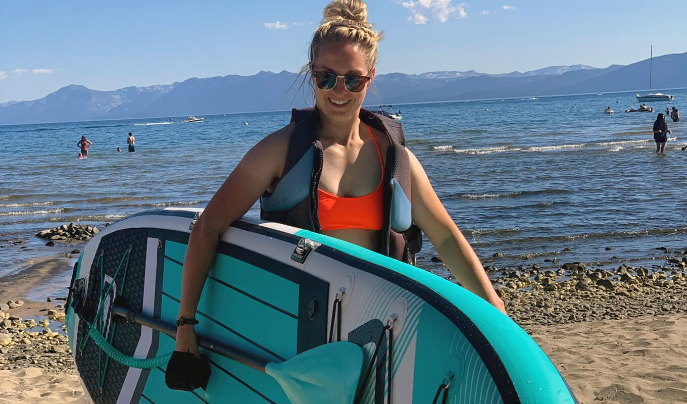 Woman wearing a life jacket while holding her paddle board