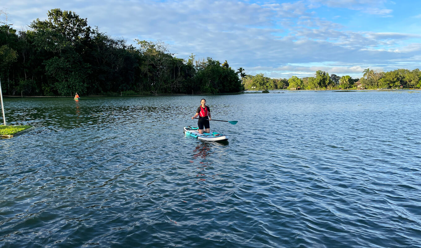 Frau, die eine Schwimmweste trägt, paddelt auf einem See