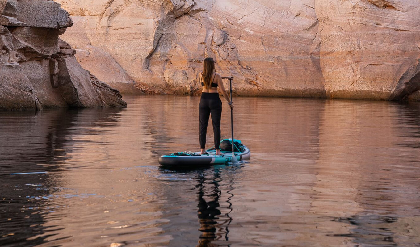 Woman paddle boarding on a lake in the middle of a rocky mountain