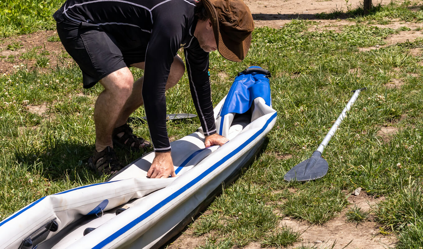 Man folding a white and blue kayak