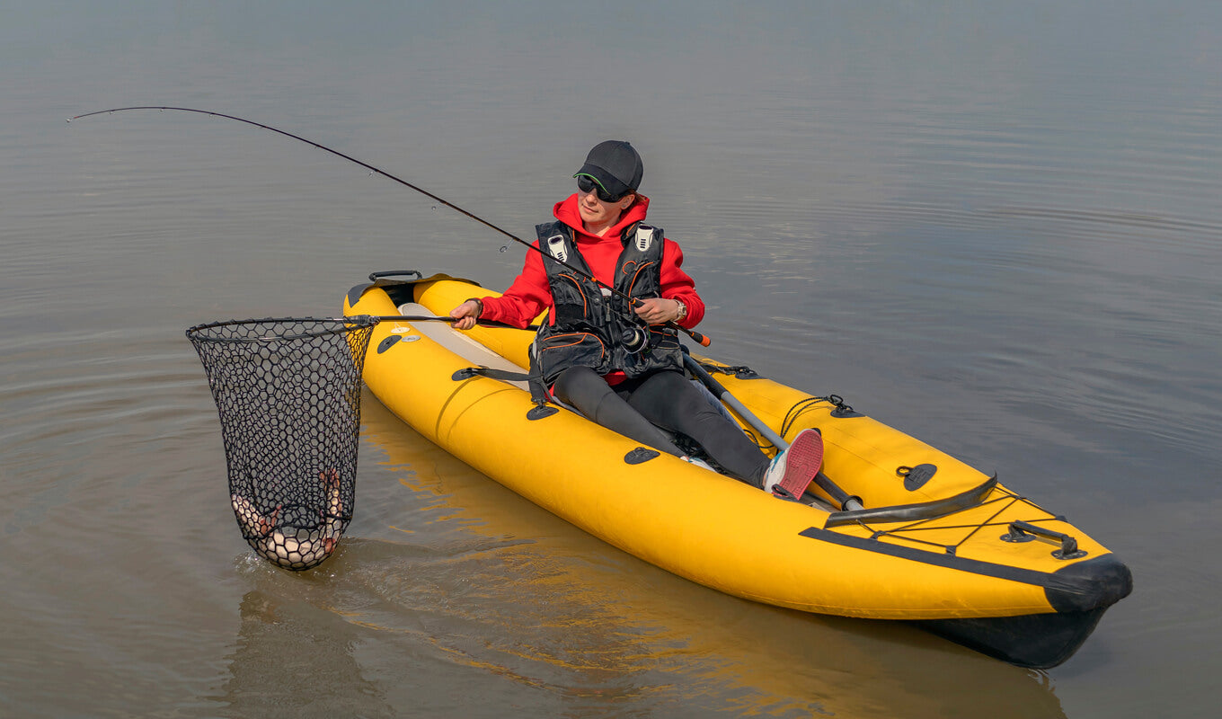 Woman catch a fish while fishing on a yellow inflatable kayak